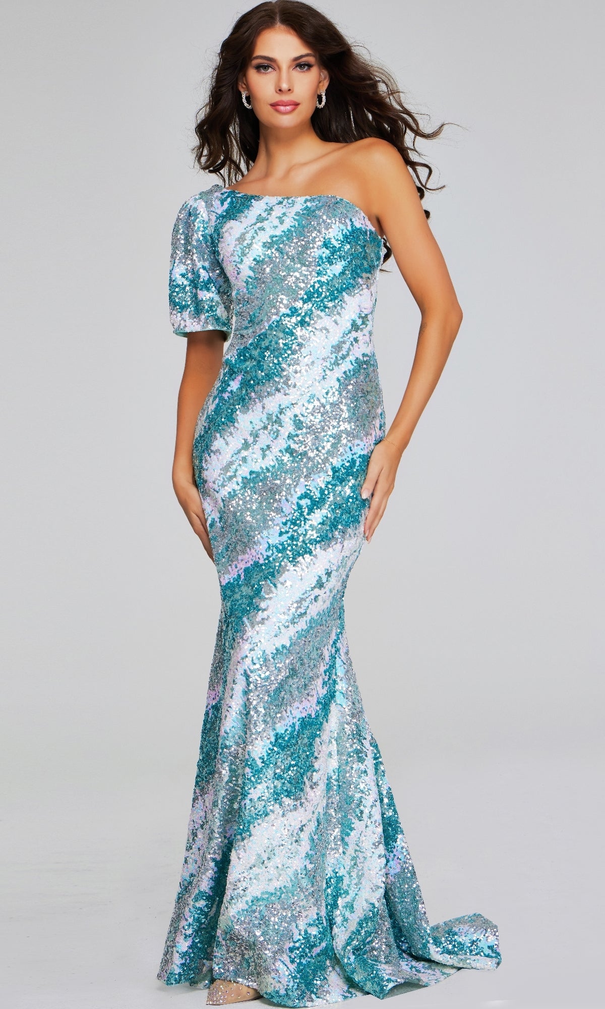 A woman poses against a plain light background wearing the Jovani 39077 long formal dress—a fit-and-flare, off-shoulder sequin gown featuring blue, silver, and white stripes.